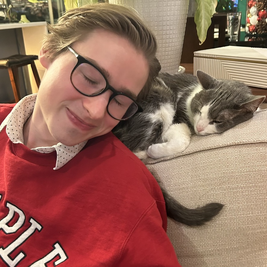 Photo of Jared Stefanowicz smiling on couch next to cat.